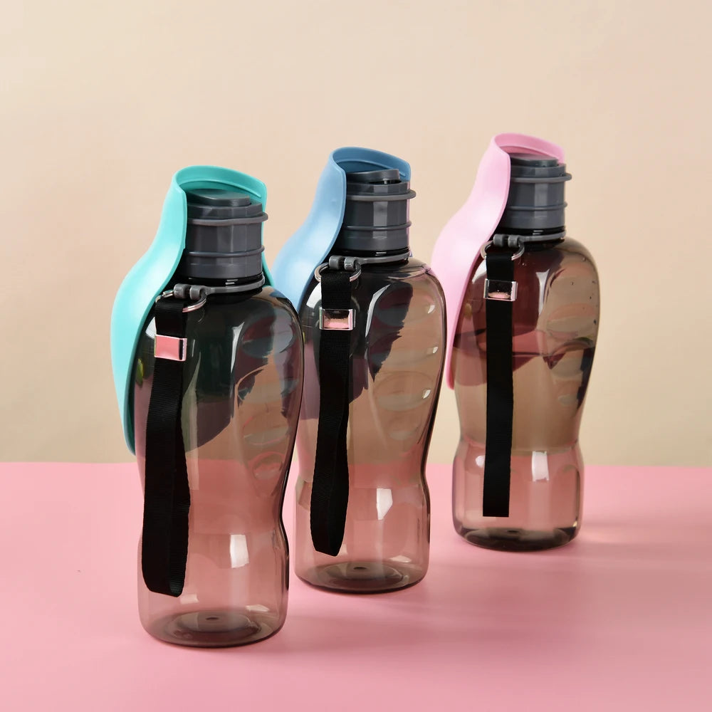 Three transparent water bottles with pastel blue, light blue, and pink flip lids and carrying straps on a pink surface.